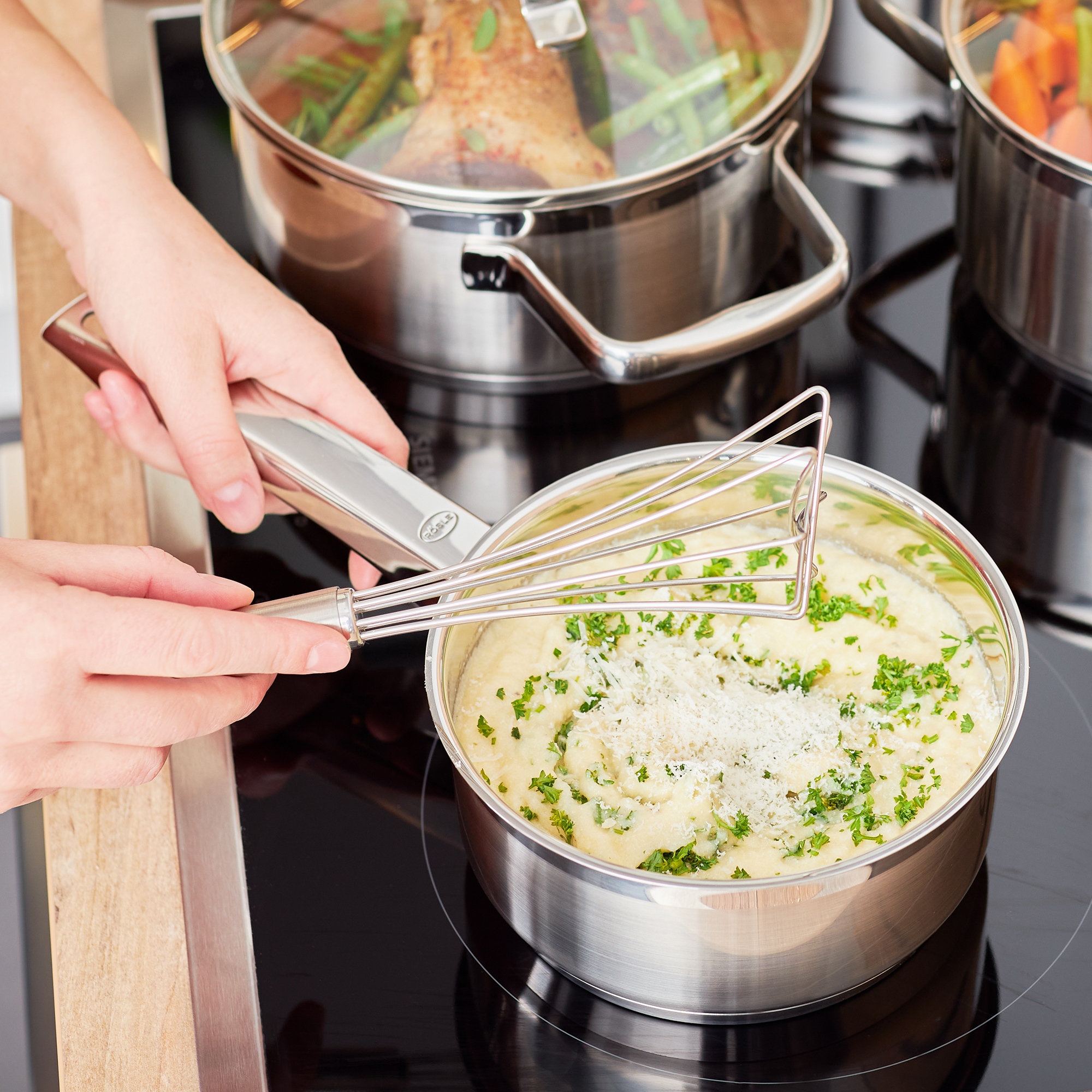 RÖSLE Stielkasserolle 16 cm mit Gemüse und Käse Stielkasserolle aus Edelstahl mit gehacktem Gemüse und Käse, auf einem Herd mit weiteren Töpfen...