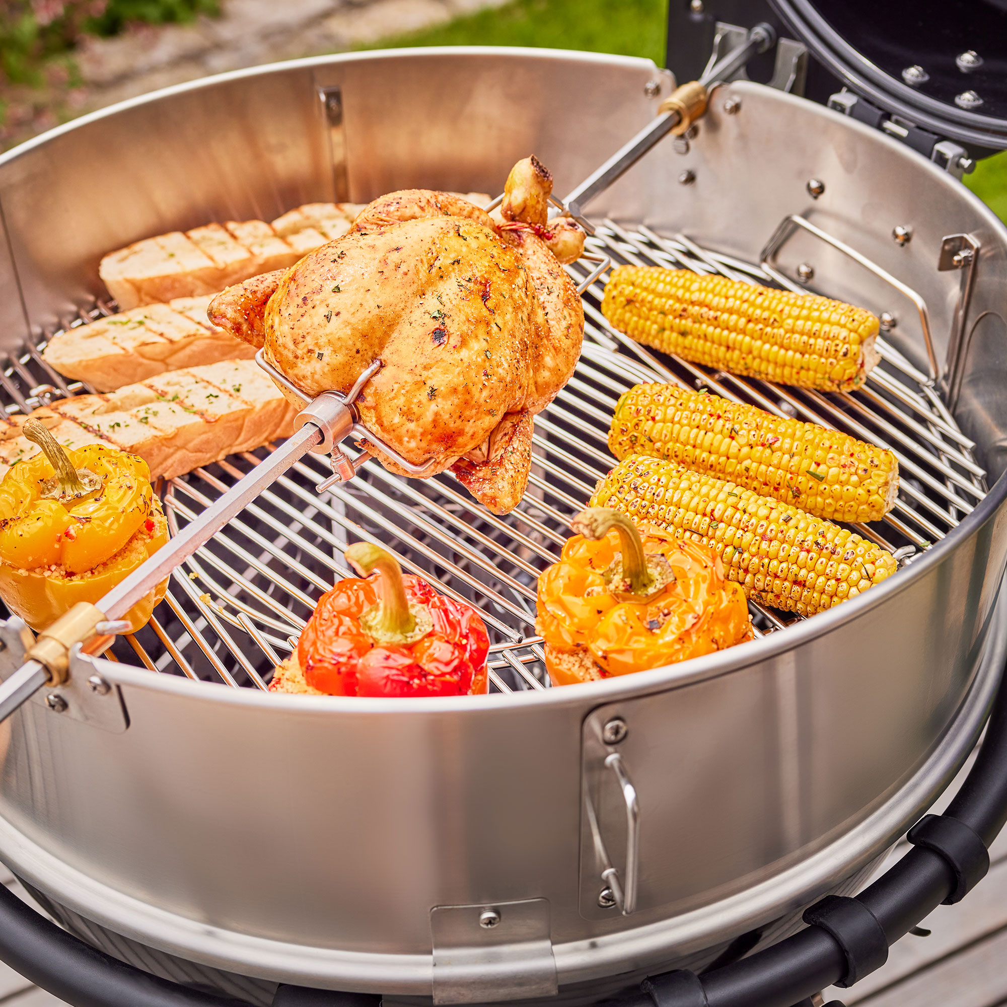 RÖSLE Holzkohle Kugelgrill mit Grillgut Holzkohle Kugelgrill mit Hähnchen, Gemüse und Maiskolben auf dem Grillrost.