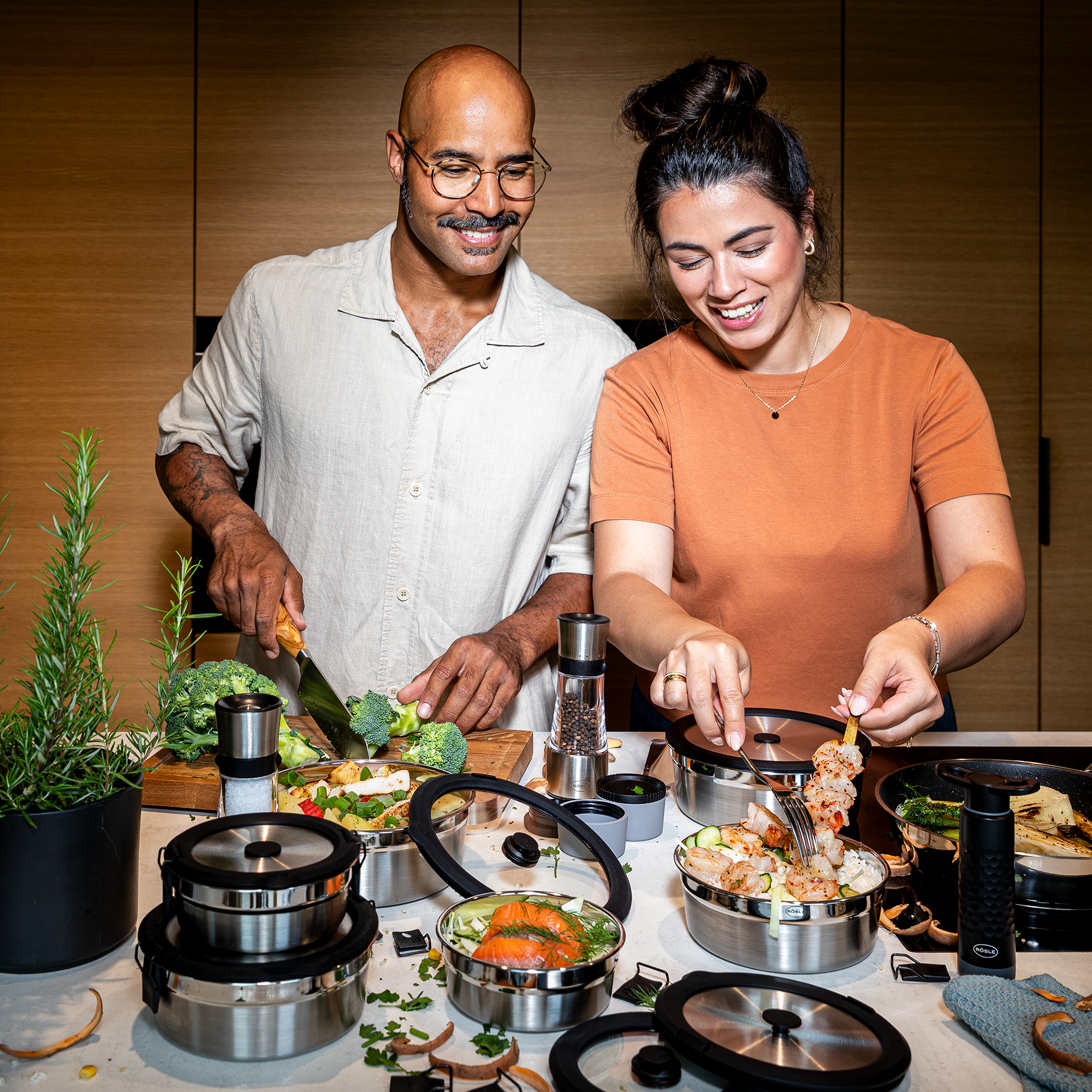 Flexx2go 0,4l Behälter, zwei Personen bereiten Essen in einer modernen Küche vor, einer schneidet Gemüse, die andere platziert Garnelen.
