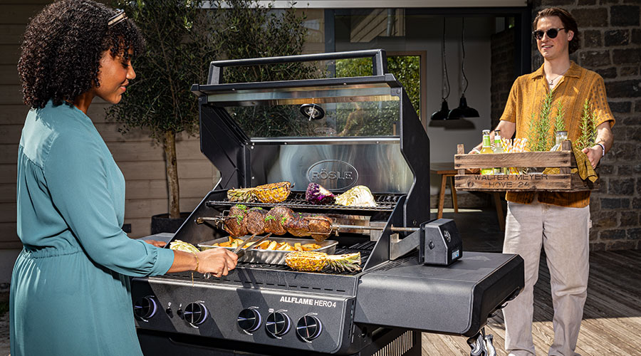 Allflame Hero 4 Frau grillt auf dem Grill und Mann trägt Tablett mit Getränken