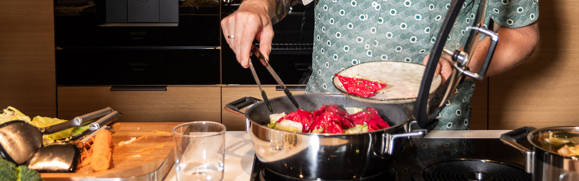 Koch mit RÖSLE Kochtopf und Tortillas Kochtopf mit Gemüse auf dem Herd, Koch hält eine Schüssel mit Tortillas in der anderen Hand.