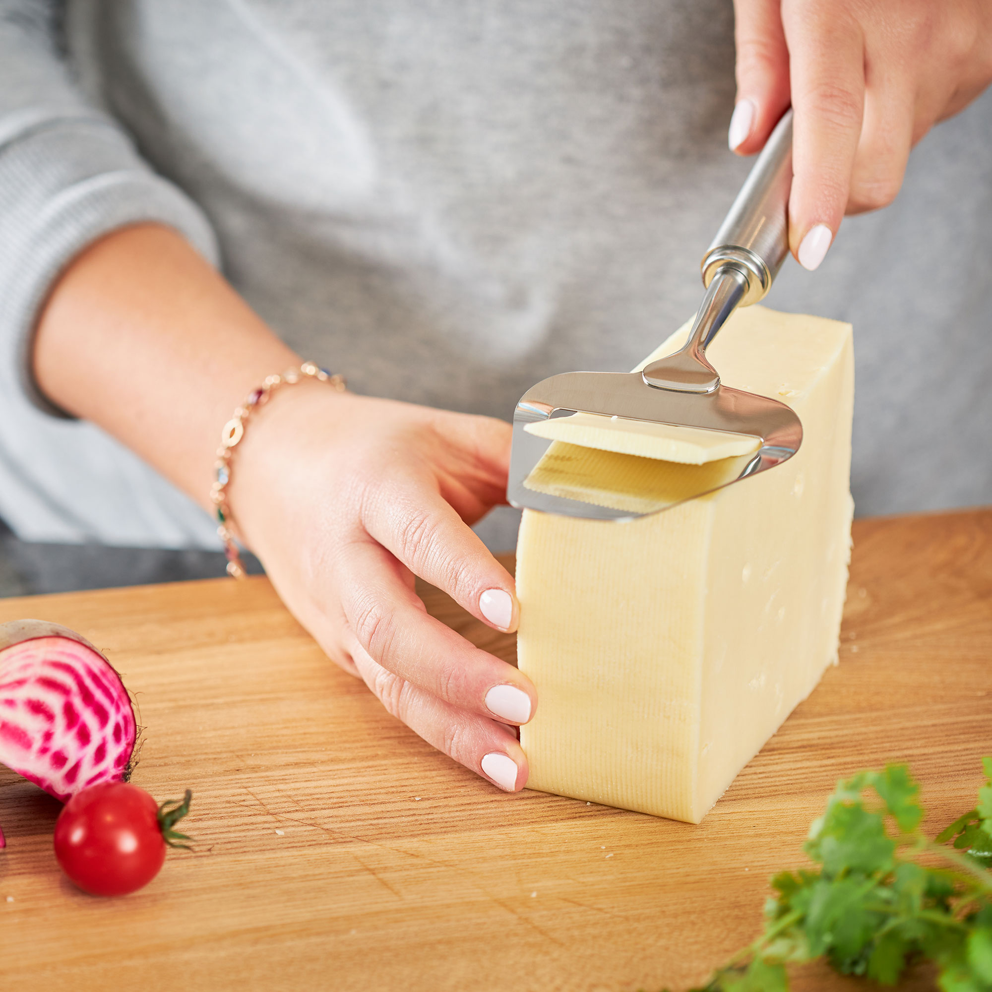 RÖSLE Käse-Set in Verwendung Käse-Set, bestehend aus einem Käsehobel, wird verwendet, um ein Stück Käse zu schneiden. Im...