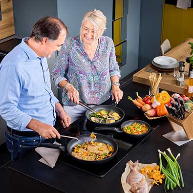 Couple cooking together in three pans Cadini series.