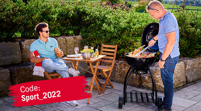 Two friends grill on the FC Bayern Edition Sport F50 charcoal kettle grill. Discount code Sport_2022