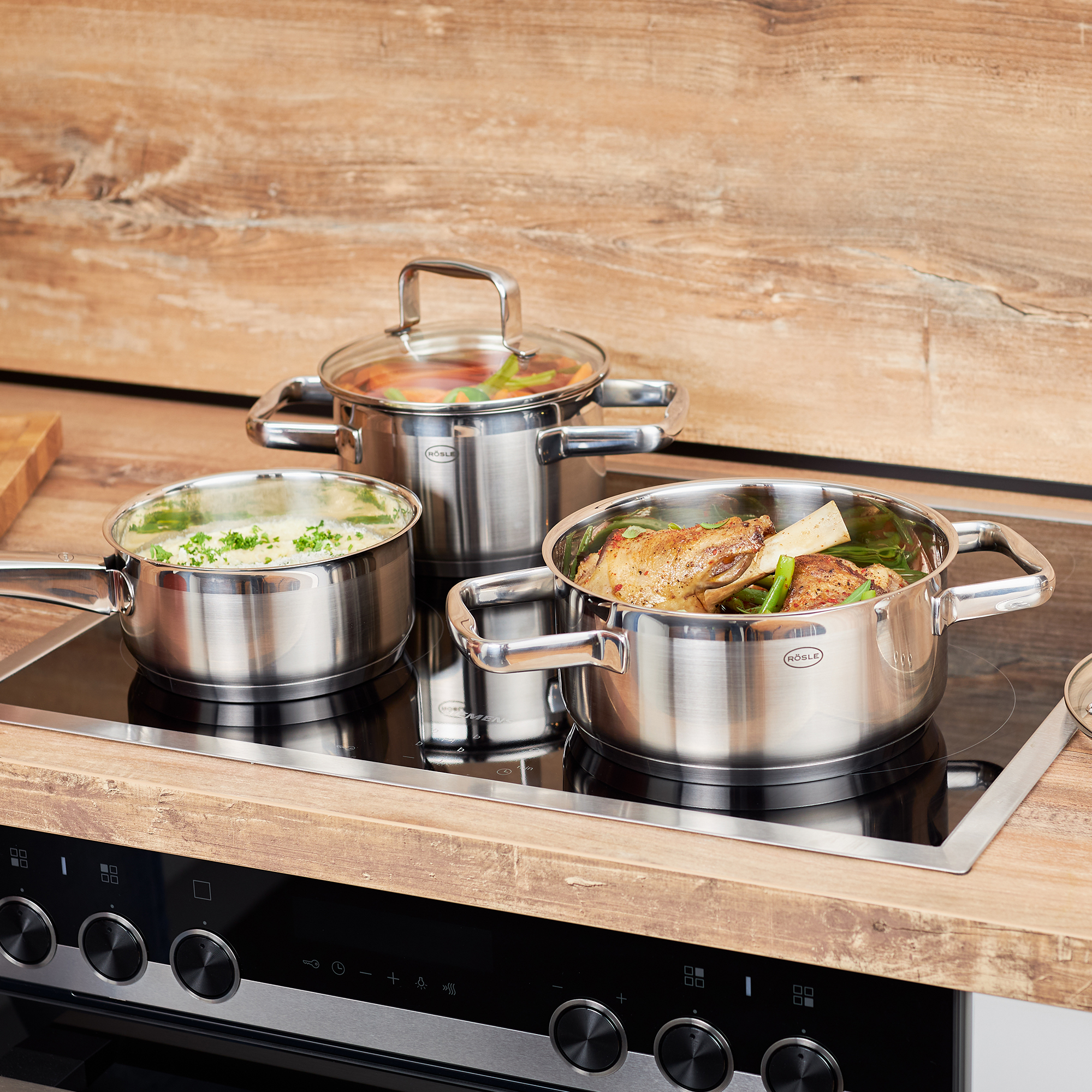 Stainless steel roasting pan, 20 cm, with lid, on a hob with vegetables and meat.