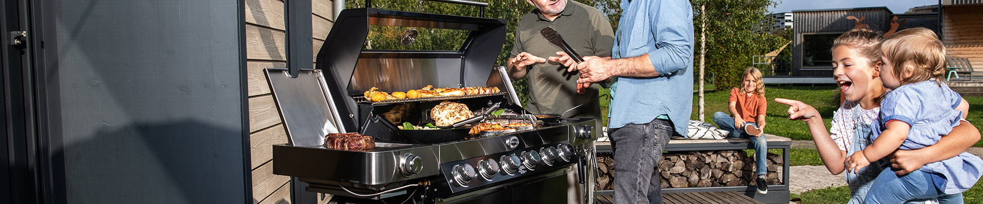 RÖSLE Gasgrill Videro in Aktion Gasgrill Videro mit gegrilltem Fleisch und Gemüse, umgeben von Personen, die das Grillen genießen.