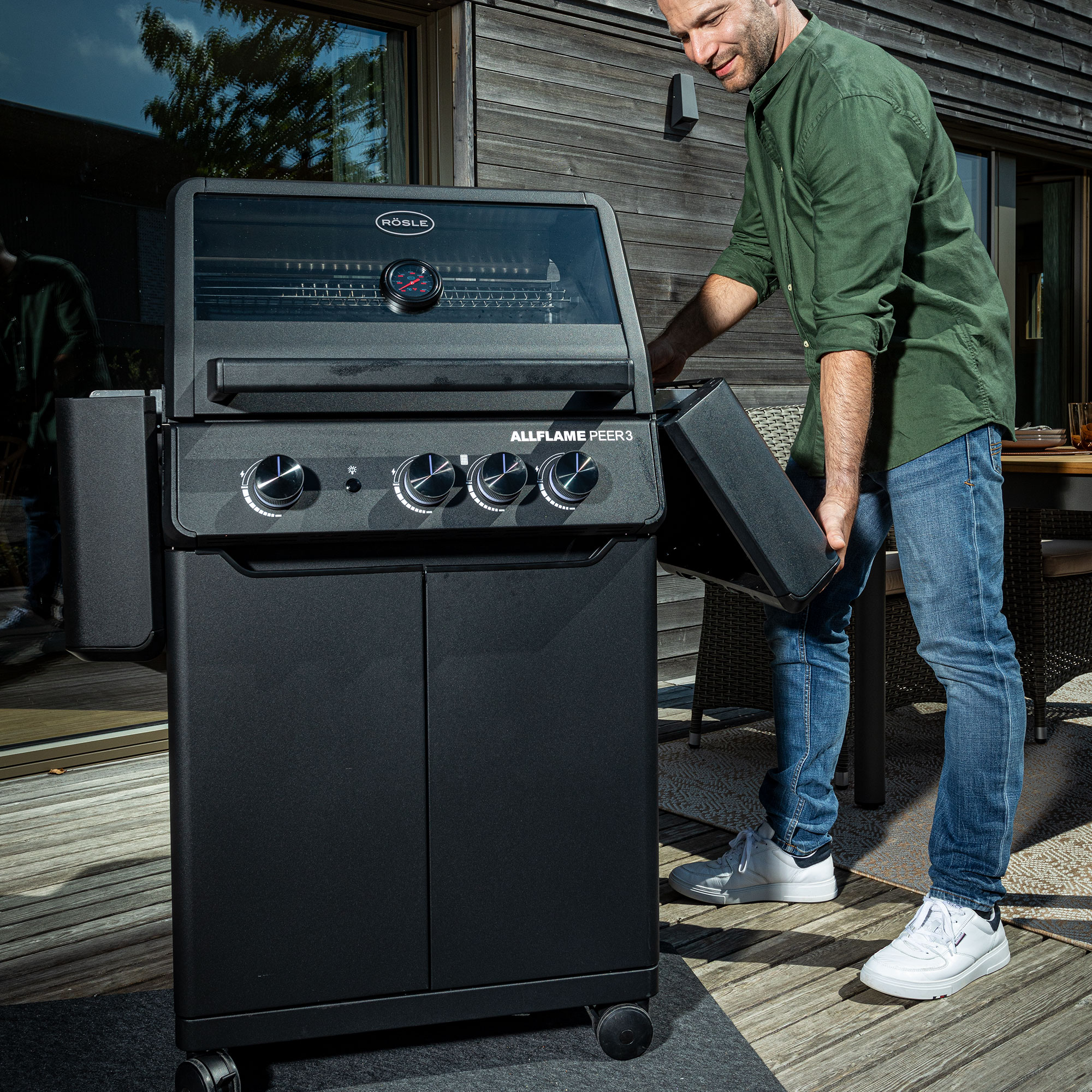 RÖSLE Allflame Peer3 Gasgrill Allflame Peer3 Gasgrill in Schwarz, mit einem Mann, der die Seitentür öffnet.