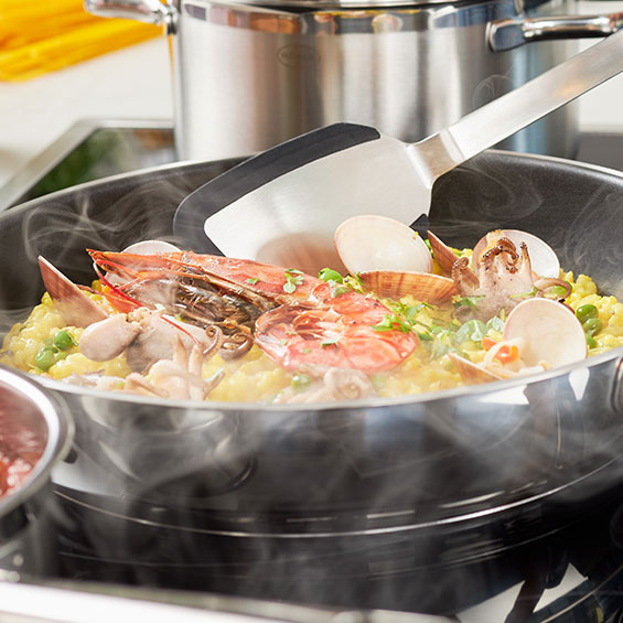 Paella wenden des Paellas mit dem Pfannenwender Silikon