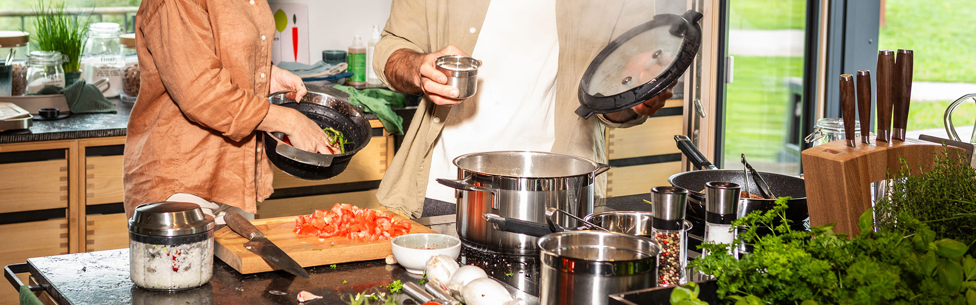 Küchenaktivität mit Töpfen und frischen Zutaten Zwei Personen in einer modernen Küche bereiten frische Zutaten vor, während sie verschiedene...