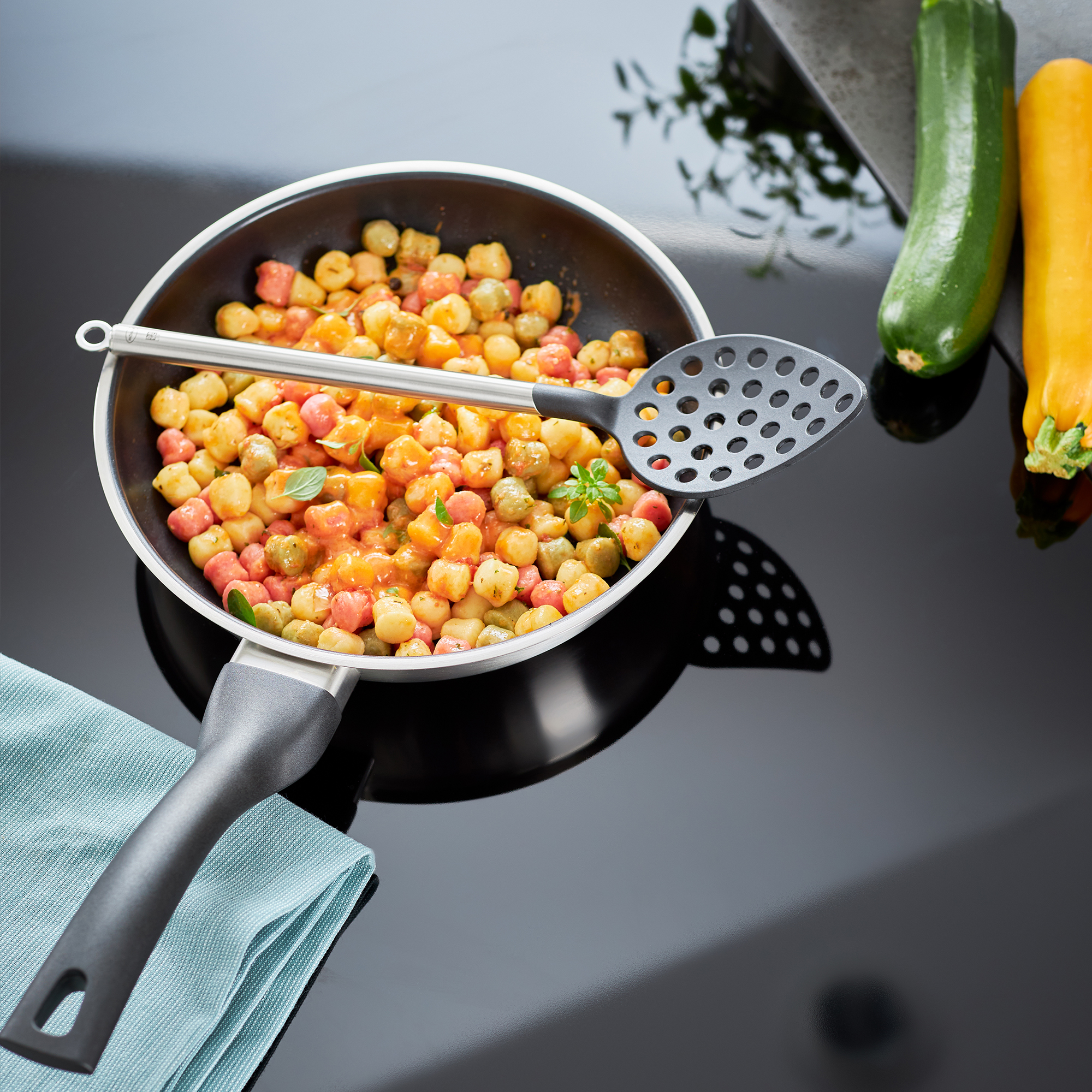 RÖSLE Bratpfanne mit Gemüse Bratpfanne 28 cm aus der ProPlex Basic Line mit Gemüse und einer Schaumkelle auf einem Tisch.