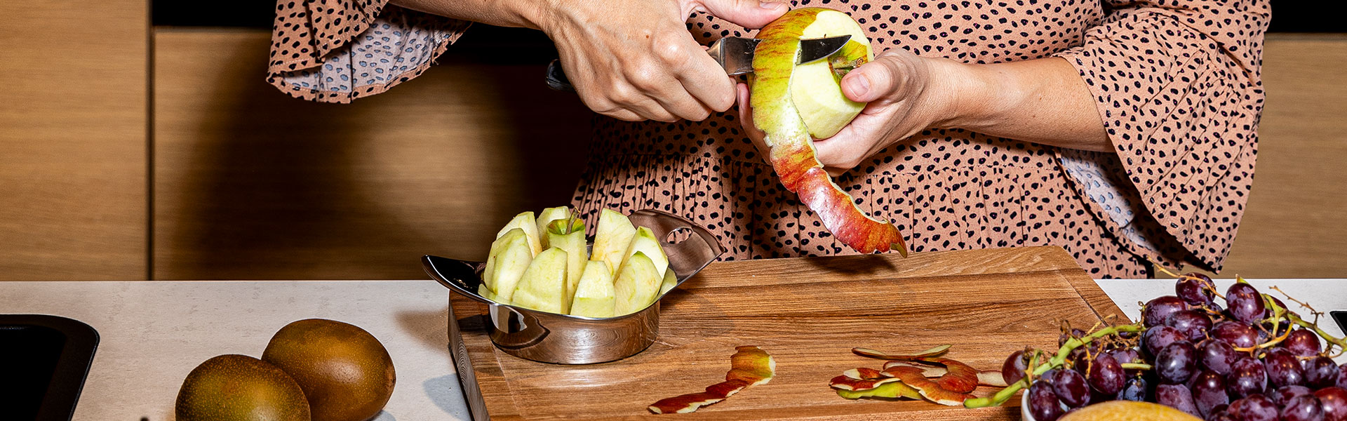 Person schält Apfel mit RÖSLE Küchenwerkzeug Küchenwerkzeug: Eine Person schält einen Apfel mit einem Messer, während geschnittene Apfelschalen...