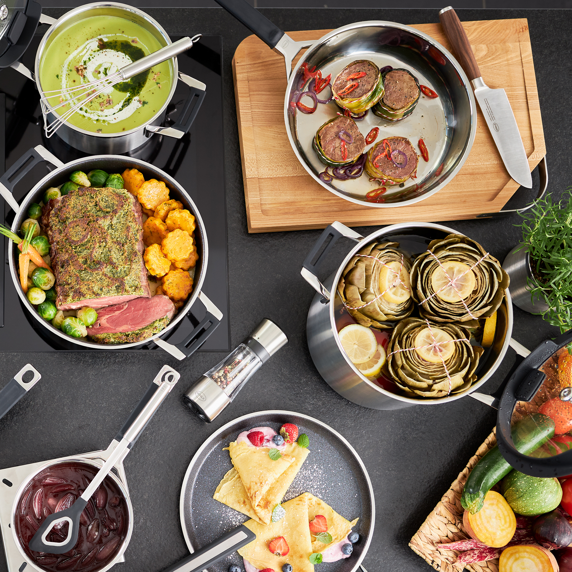 RÖSLE frying pan with prepared food Stainless steel frying pan with various dishes such as vegetables, meat and desserts on one...