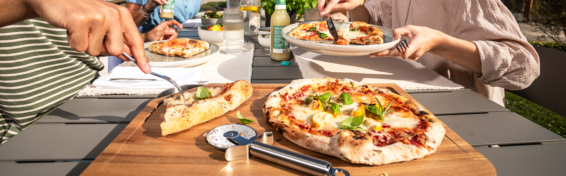 Rezepte Grillen Pizza mit Pizzaschneider auf einem Schneidbrett