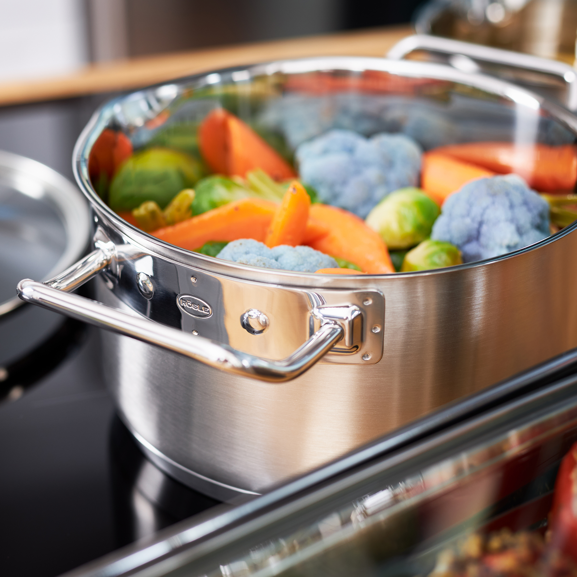 RÖSLE Kochtopf 24 cm mit Gemüse Kochtopf, 24 cm, aus Edelstahl, mit Glasdeckel, gefüllt mit buntem Gemüse.