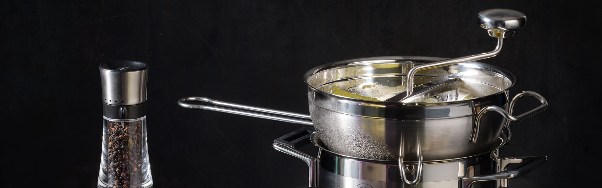 RÖSLE Edelstahl Siebtrichter mit Rührwerk Siebtrichter aus Edelstahl mit einem langen Griff und einem Rührwerk, neben einem Pfeffermühlen-Behälter.