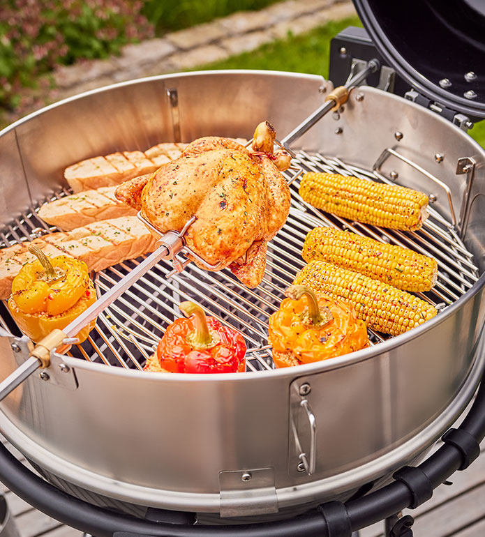 Chicken on rotisserie, as well as corn on the cob, baguette and stuffed peppers on kettle grill AIR F60