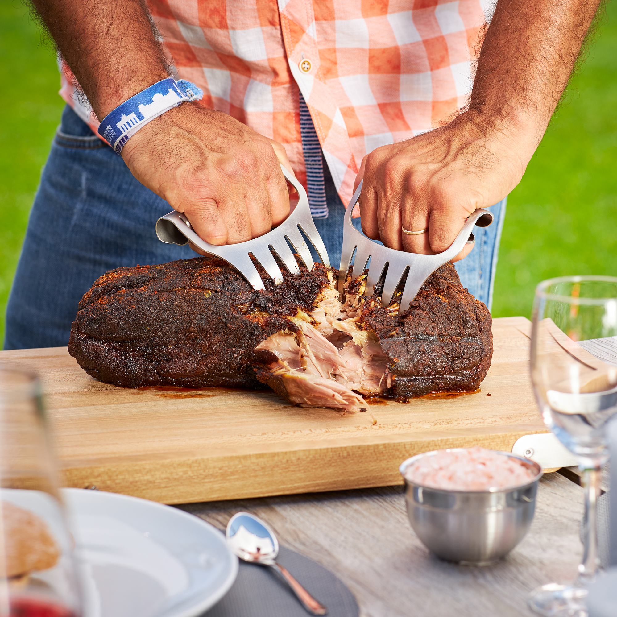 Stainless steel pulled pork forks from RÖSLE Stainless steel pulled pork forks in action while a person cuts meat on a wooden board.