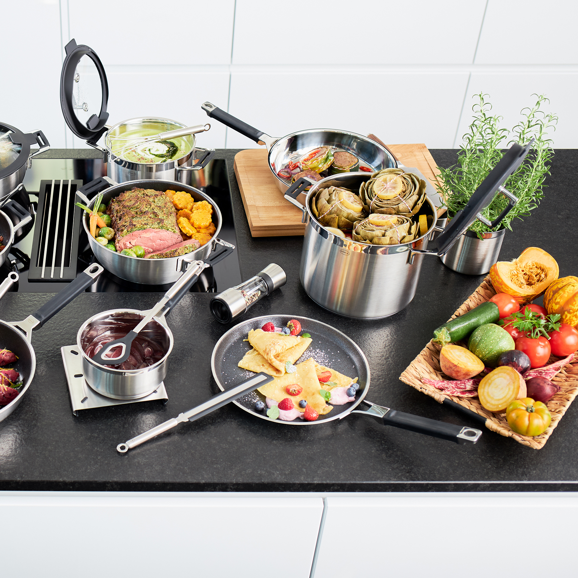 RÖSLE Kochtopf und verschiedene Gerichte auf der Arbeitsplatte Kochtopf 24 cm hoch aus Edelstahl, umgeben von verschiedenen Gerichten und Zutaten auf einer...