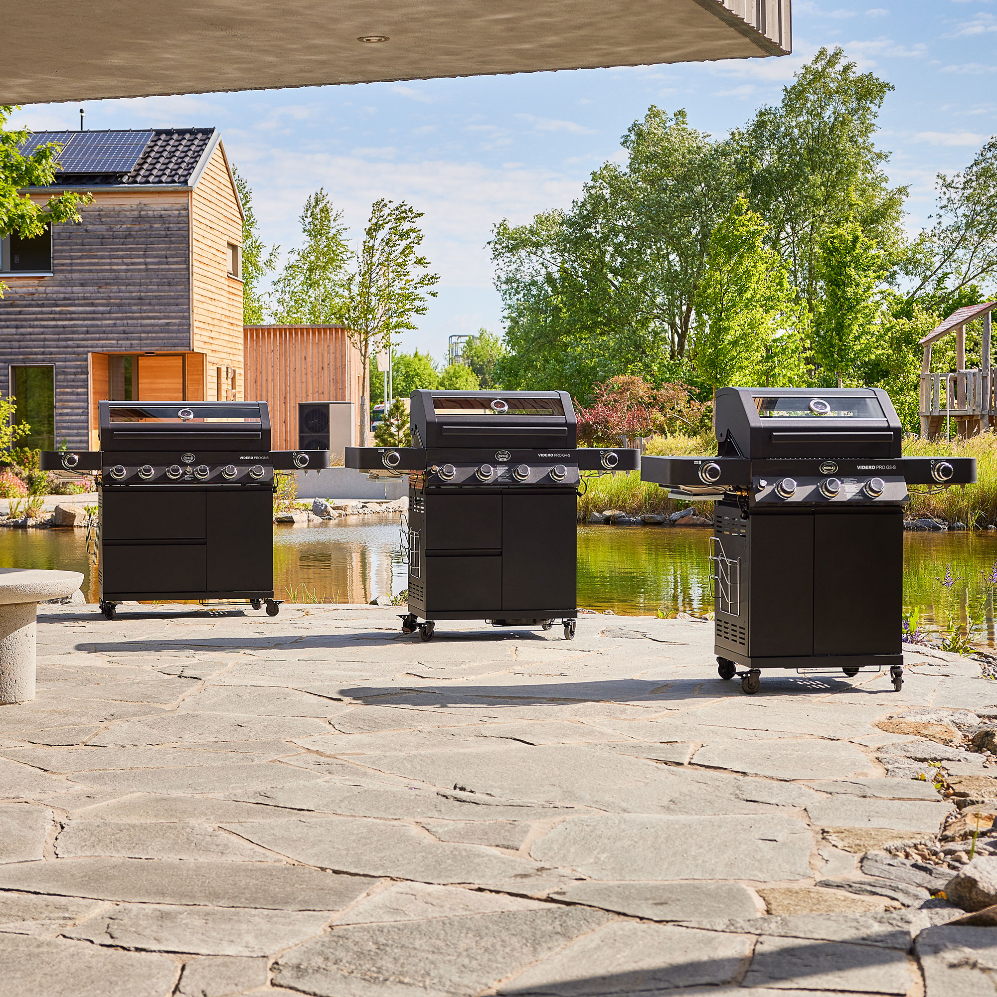 RÖSLE Gasgrill Videro G6-S PRO am Wasser Gasgrill Videro G6-S PRO in Schwarz, dreifach angeordnet am Wasser.
