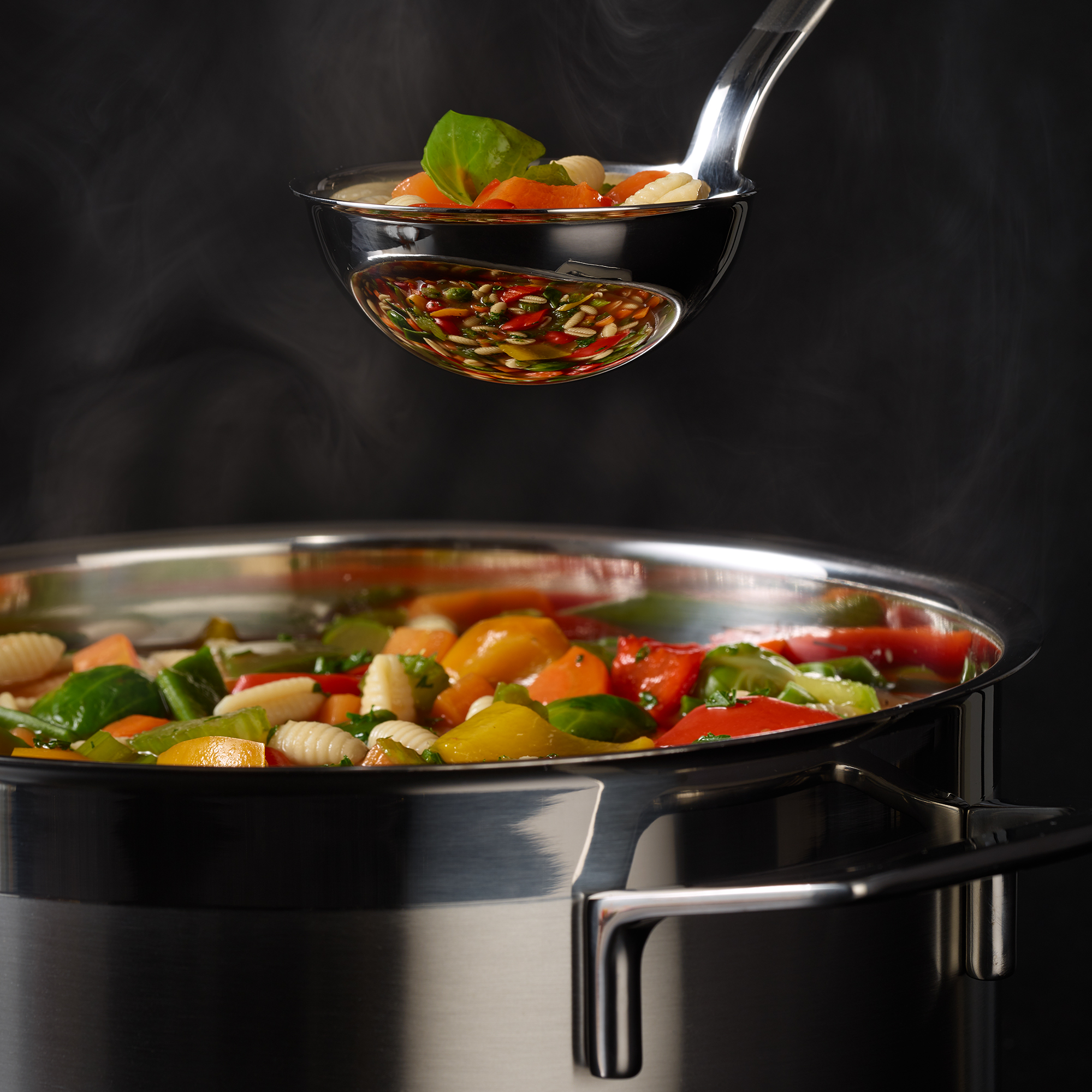 RÖSLE ladle with vegetables Stainless steel ladle, 7 cm, with vegetables and herbs, over a pot with colourful vegetables.