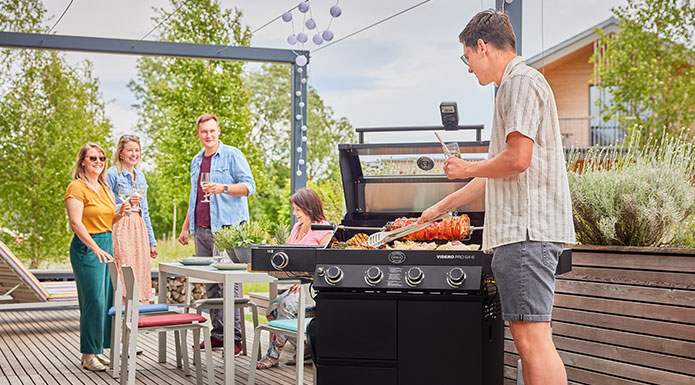 Grillmeister und Anfänger Freunde grillen zusammen auf der Terrasse
