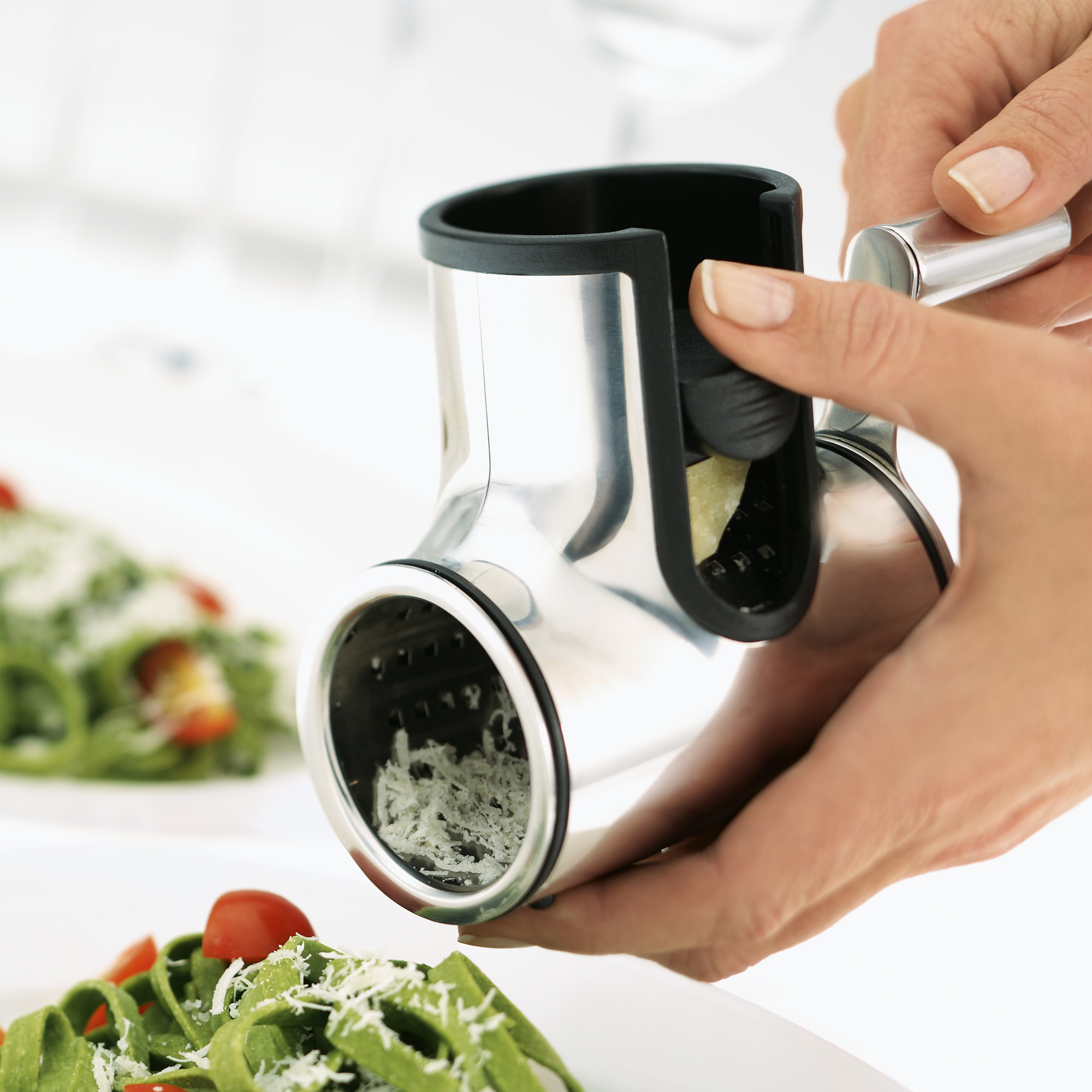 RÖSLE Käsereibe Käsereibe aus Edelstahl, in der Hand gehalten, mit geriebenem Käse über einem Salat.