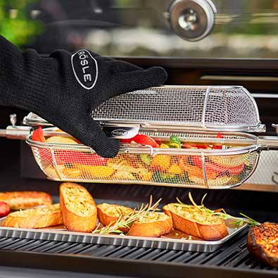 Vegetables in the rotating spit basket , which is opened with a grill glove.