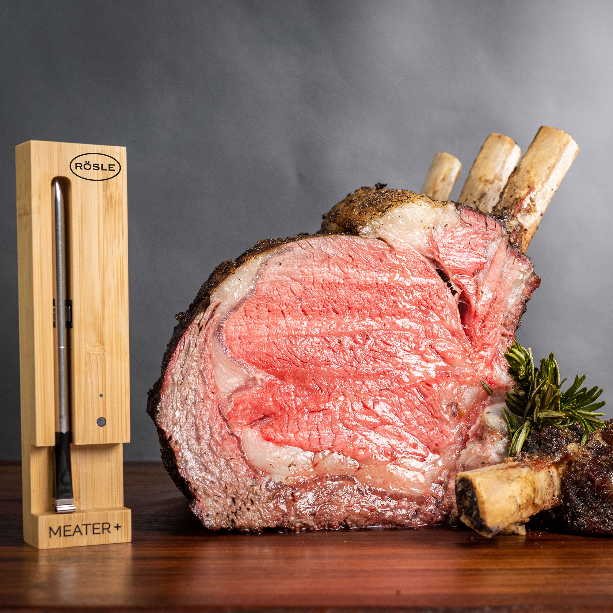 Rinderbraten mit RÖSLE MEATER+ MEATER+ neben einem perfekt gegarten Rinderbraten mit rosa Fleisch und Knochen.