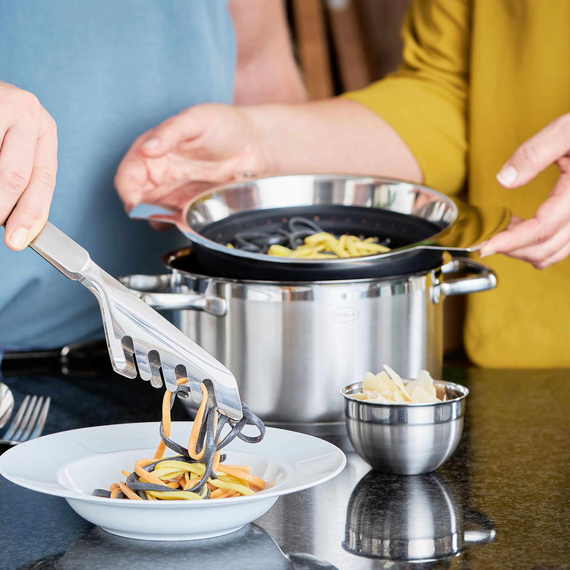 RÖSLE faltbarer Seiher in Aktion faltbarer Seiher in Schwarz, verwendet zum Abgießen von Nudeln aus einem Topf, während eine...