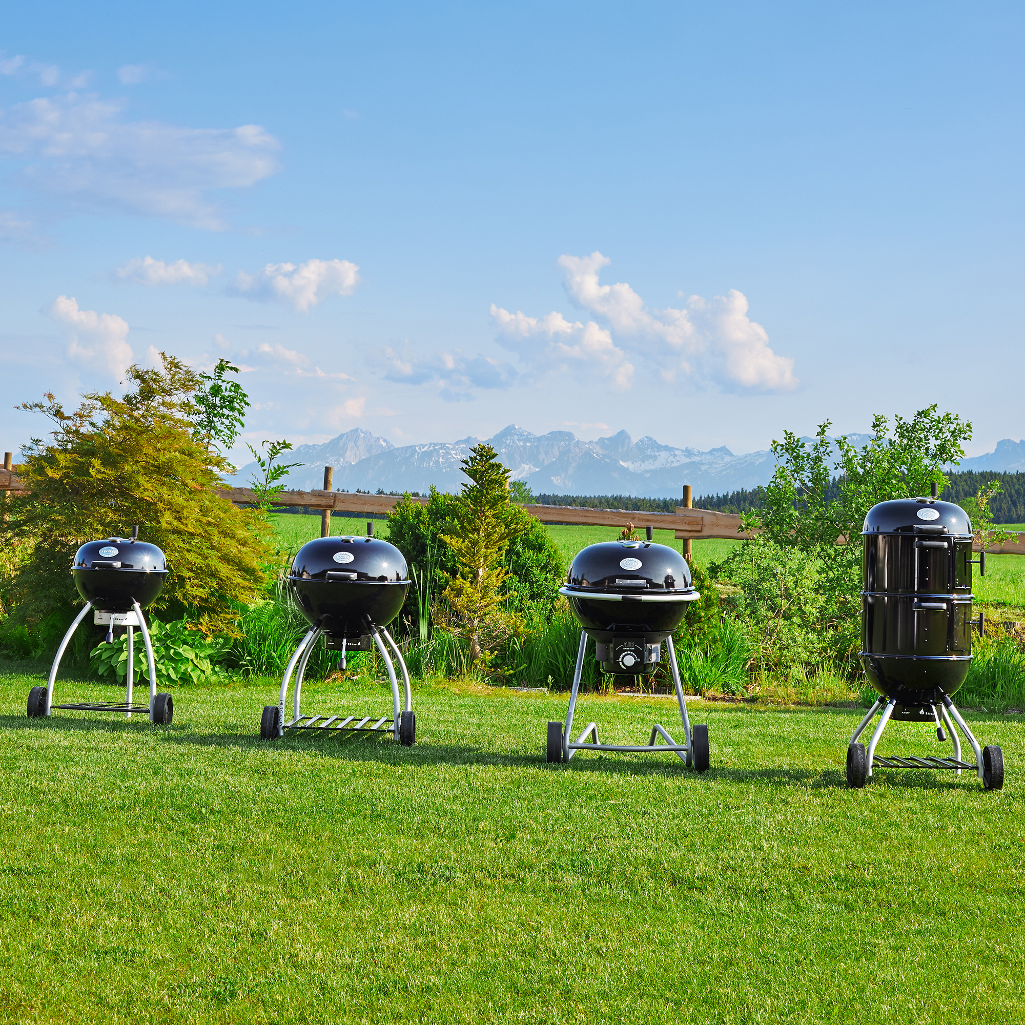 RÖSLE outdoor charcoal kettle barbecues Charcoal kettle barbecues in various models on a meadow with a mountain landscape in the background.