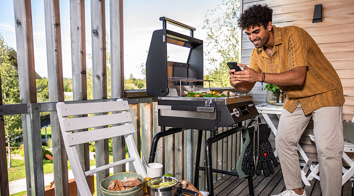 Elektrogrill E2-P Mann fotografiert Grillgut auf dem Elektrogrill mit dem Handy