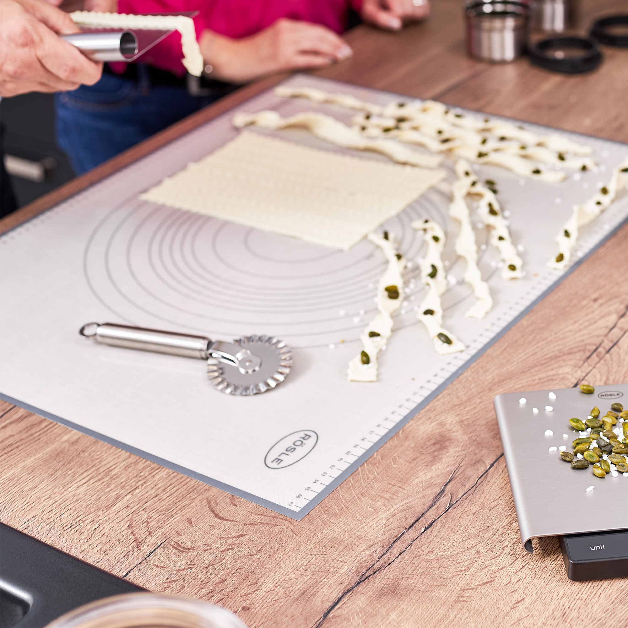 Pastry mat and pastry wheel from RÖSLE Dough mat with pieces of dough and a dough wheel on a wooden work surface.