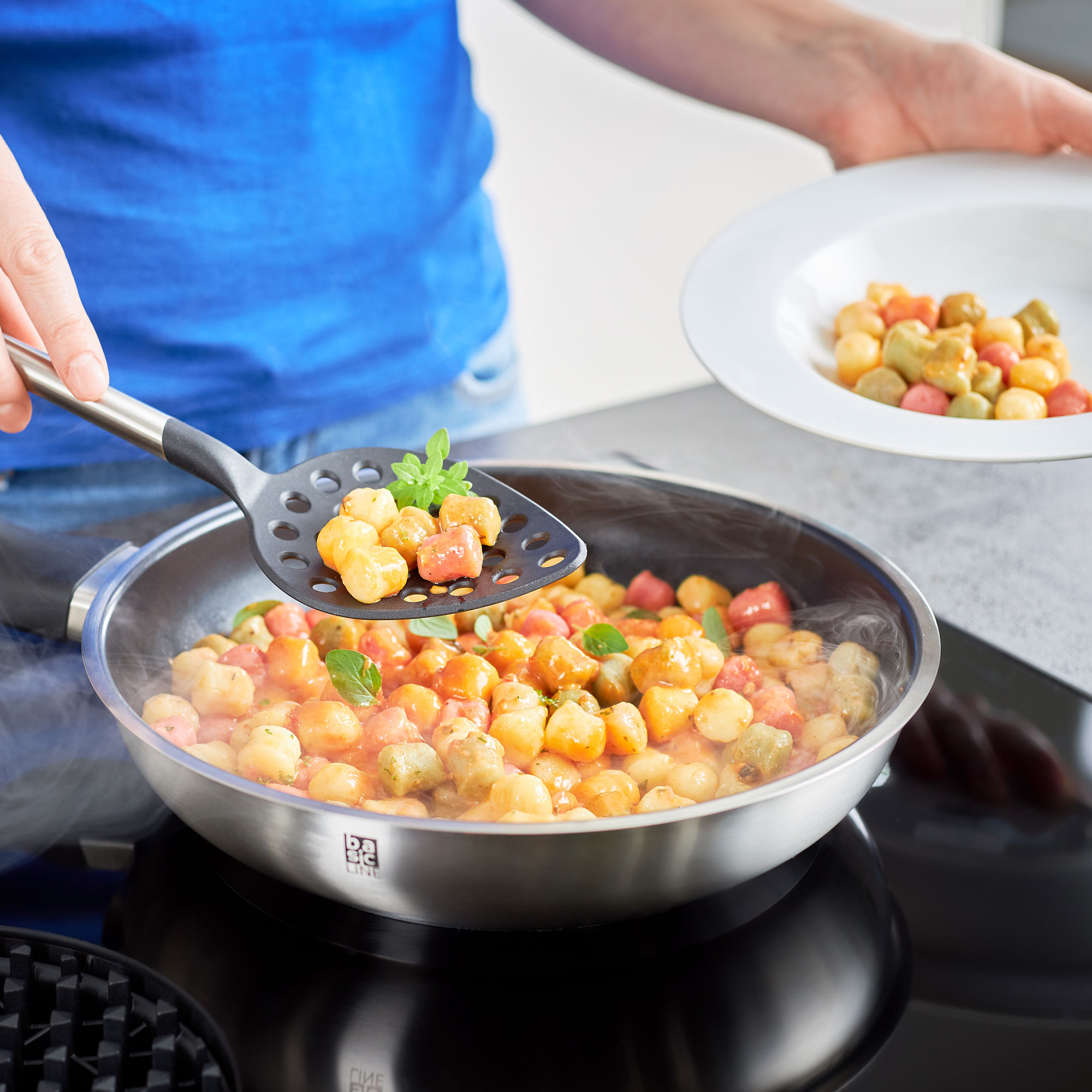 Gourmet Set mit Pasta in einer Pfanne, Gnocchi werden mit einem Schöpflöffel serviert.