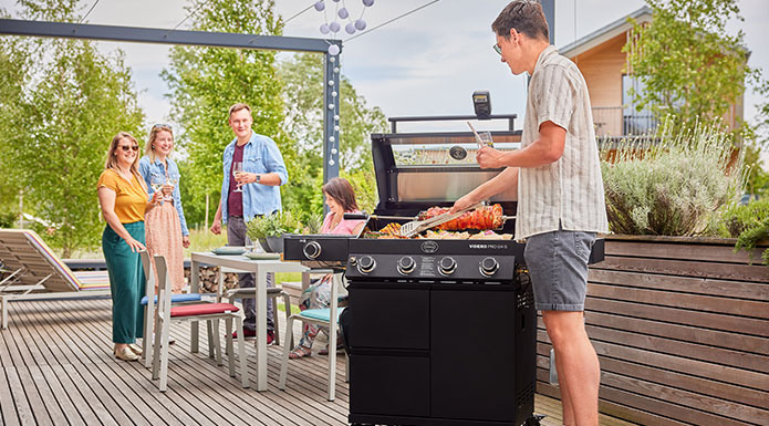 Grillen mit Freunden 5 Freunde grillen zusammen auf der Terrasse und unterhalten sich.