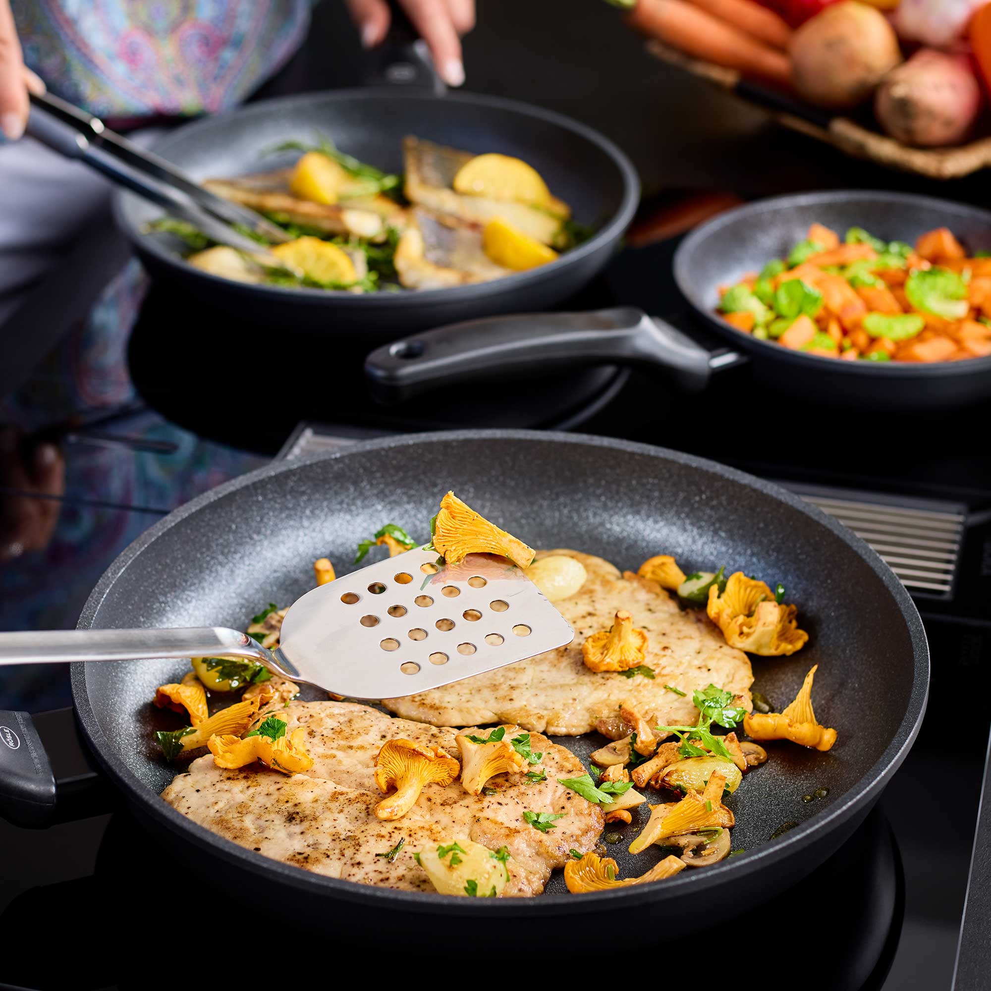 RÖSLE Bratpfanne Cadini mit gebratenem Fisch Bratpfanne Cadini, 28 cm, mit gebratenem Fisch und Pfifferlingen, Kochutensilien im Einsatz.