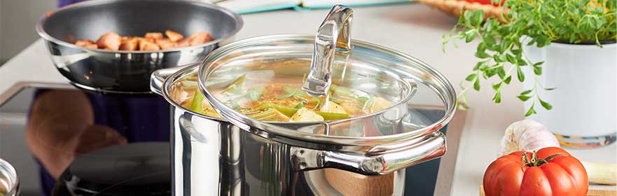 RÖSLE Elegance Kochtopf Elegance Kochtopf aus Edelstahl mit Glasdeckel, gefüllt mit Gemüse auf einem Herd.