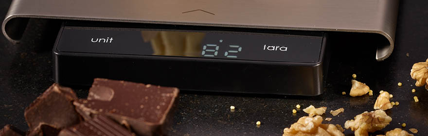 RÖSLE digitale keukenweegschaal Keukenweegschaal met digitaal display, omringd door stukjes chocolade en noten.