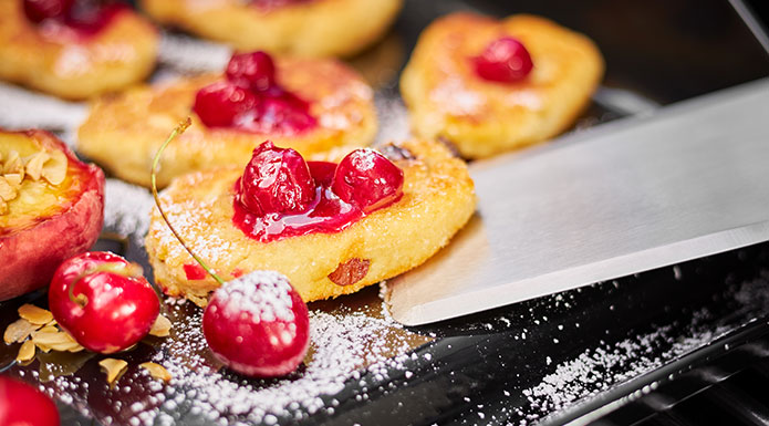 Curd pancakes with cherries and powdered sugar on the plancha griddle