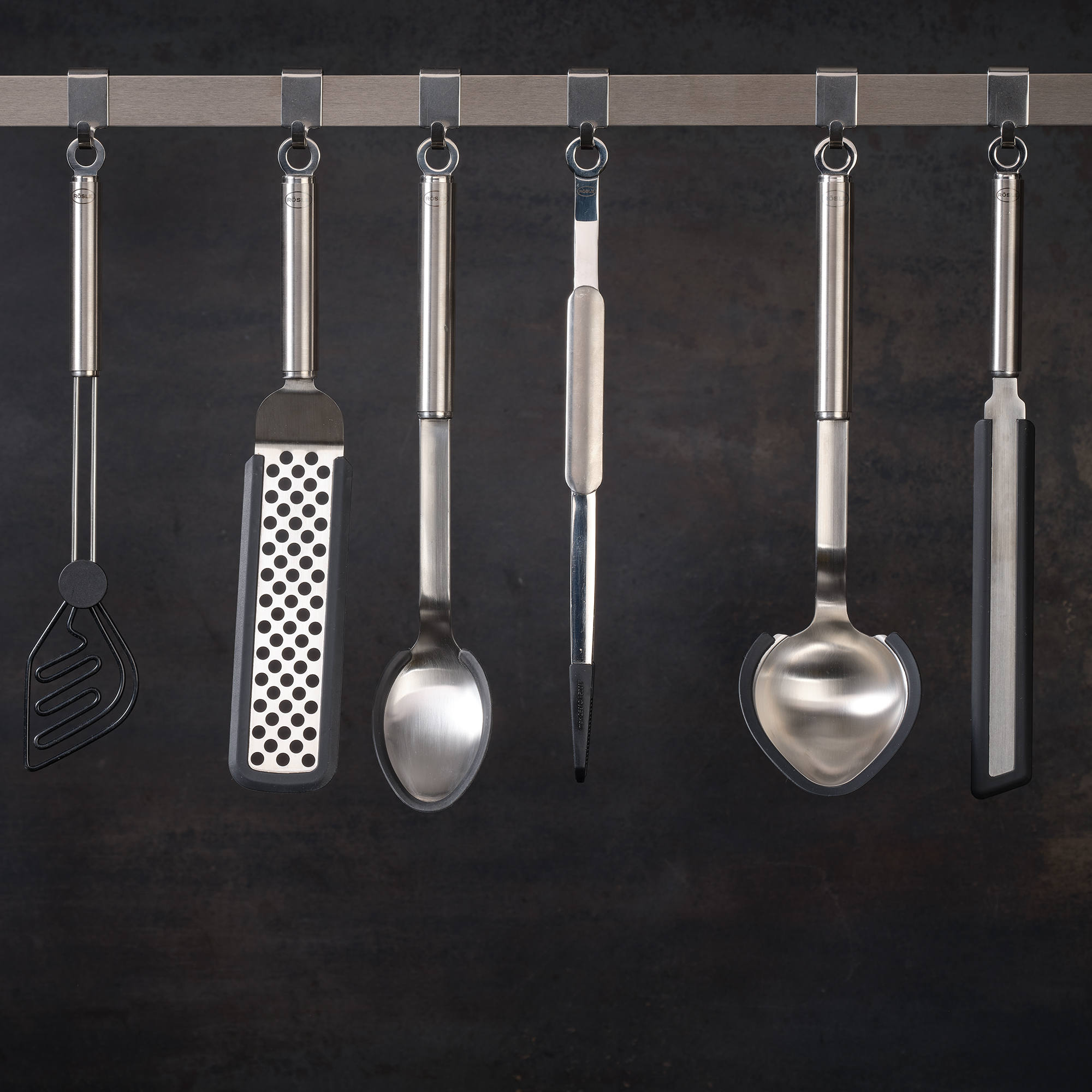 RÖSLE stainless steel kitchen utensils Stainless steel kitchen utensils, including turner, grater, spoon and ladle, on a hanger.