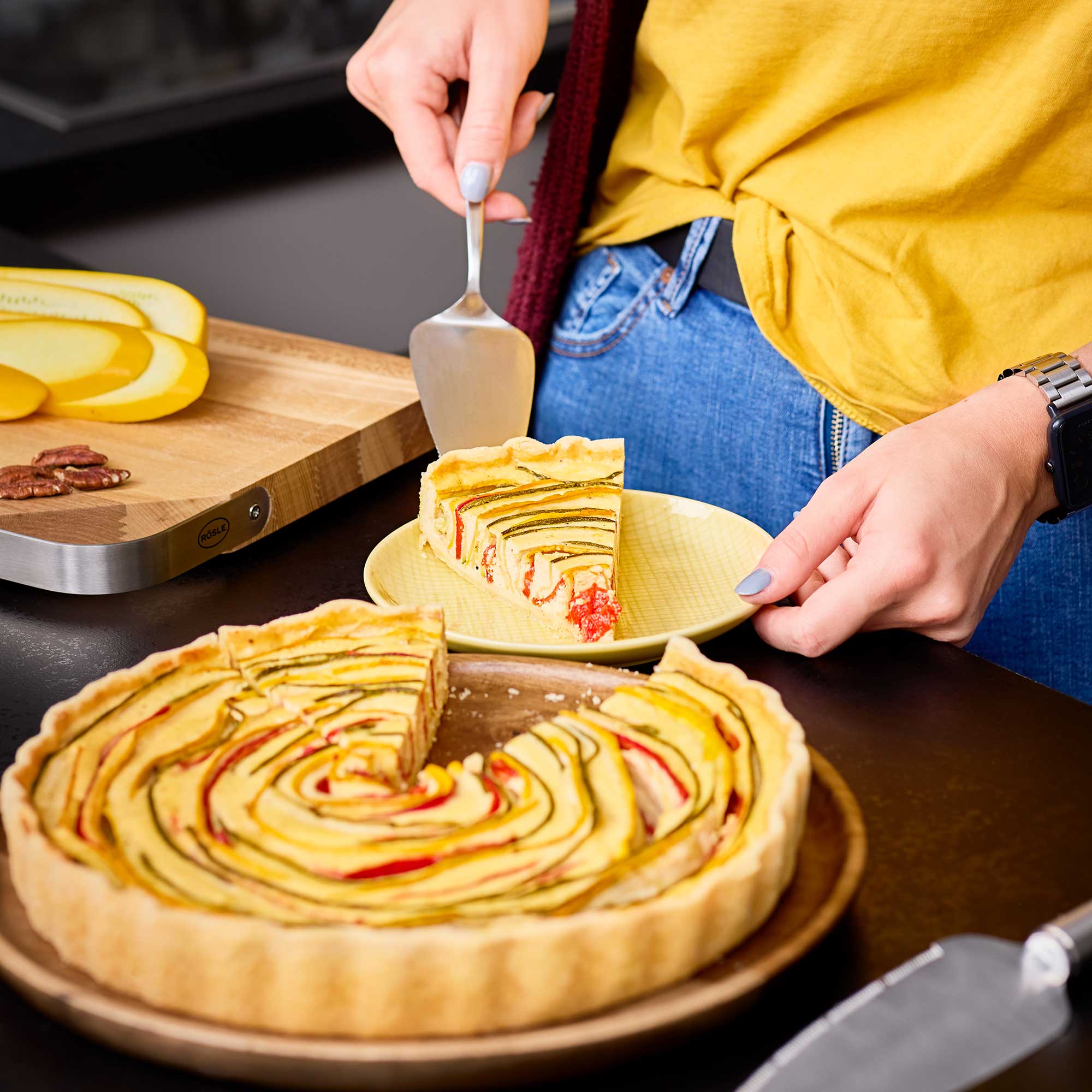 RÖSLE Tortenschaufel beim Servieren einer Torte Tortenschaufel in Gebrauch, um ein Stück einer bunten Torte auf einen Teller zu heben.