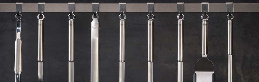 RÖSLE Küchenzubehör mit runden Griffen Küchenzubehör mit runden Griffen, aus Edelstahl, an einer Halterung aufgehängt.