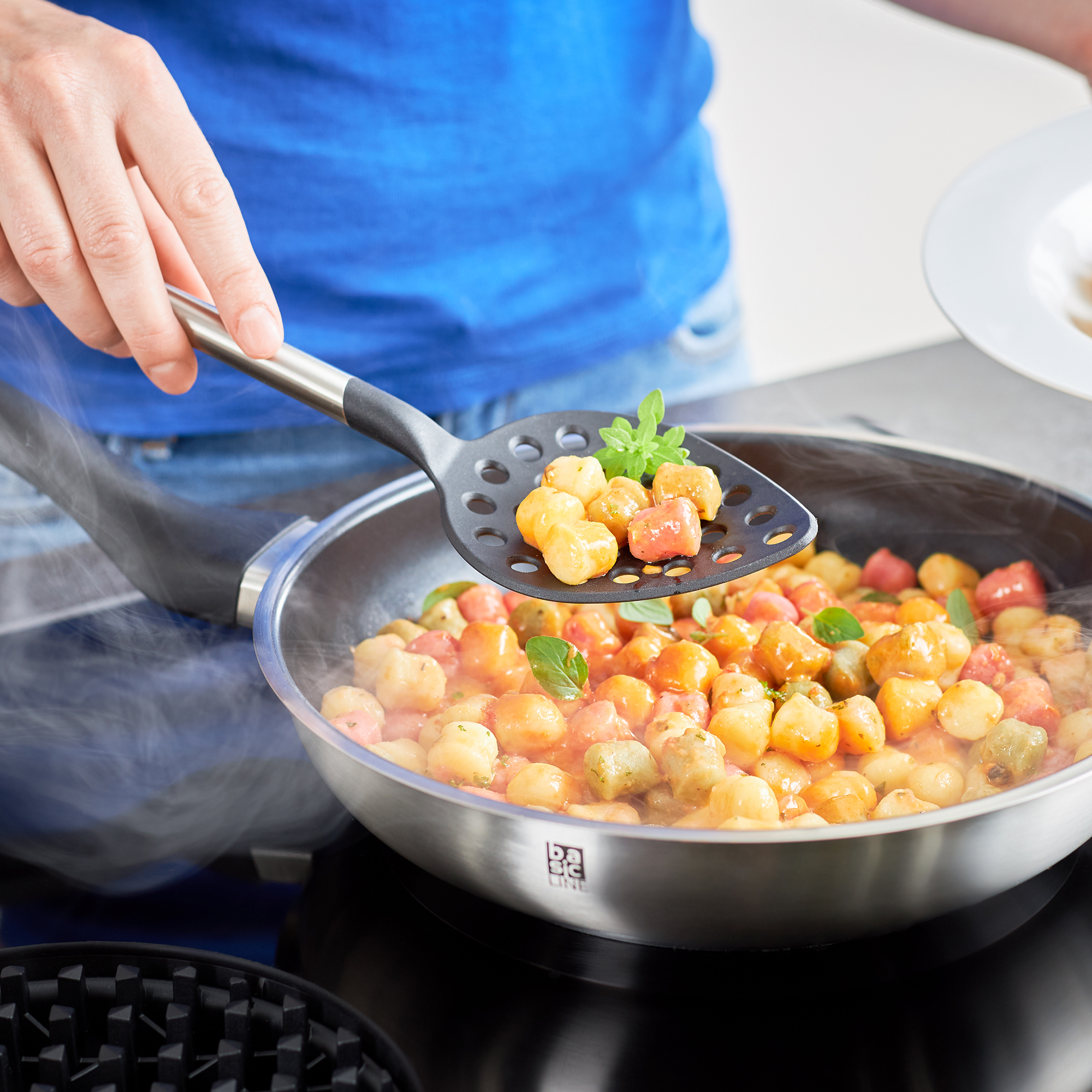 RÖSLE Schaumlöffel in Aktion Schaumlöffel aus Edelstahl, 32 cm, beim Servieren von buntem Gemüse aus einer Pfanne.