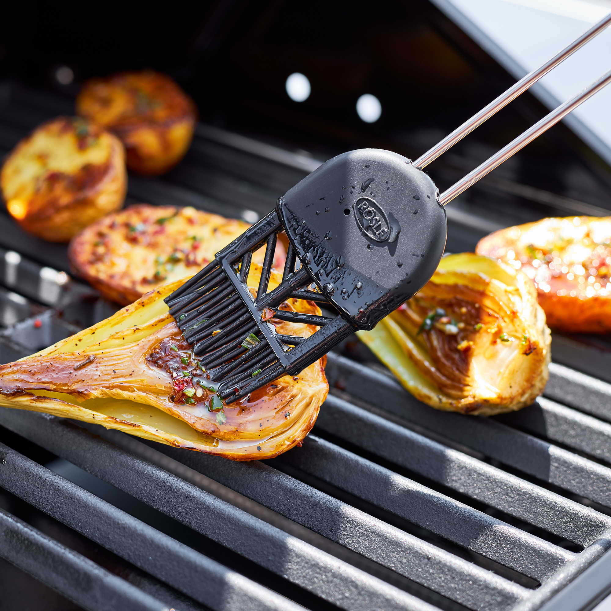 RÖSLE silicone baking brush on the grill Silicone pastry brush in black, used to brush grilled vegetables on a grill rack.