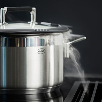 Steam from cooking pot is drawn down into a fume hood integrated into the stove.