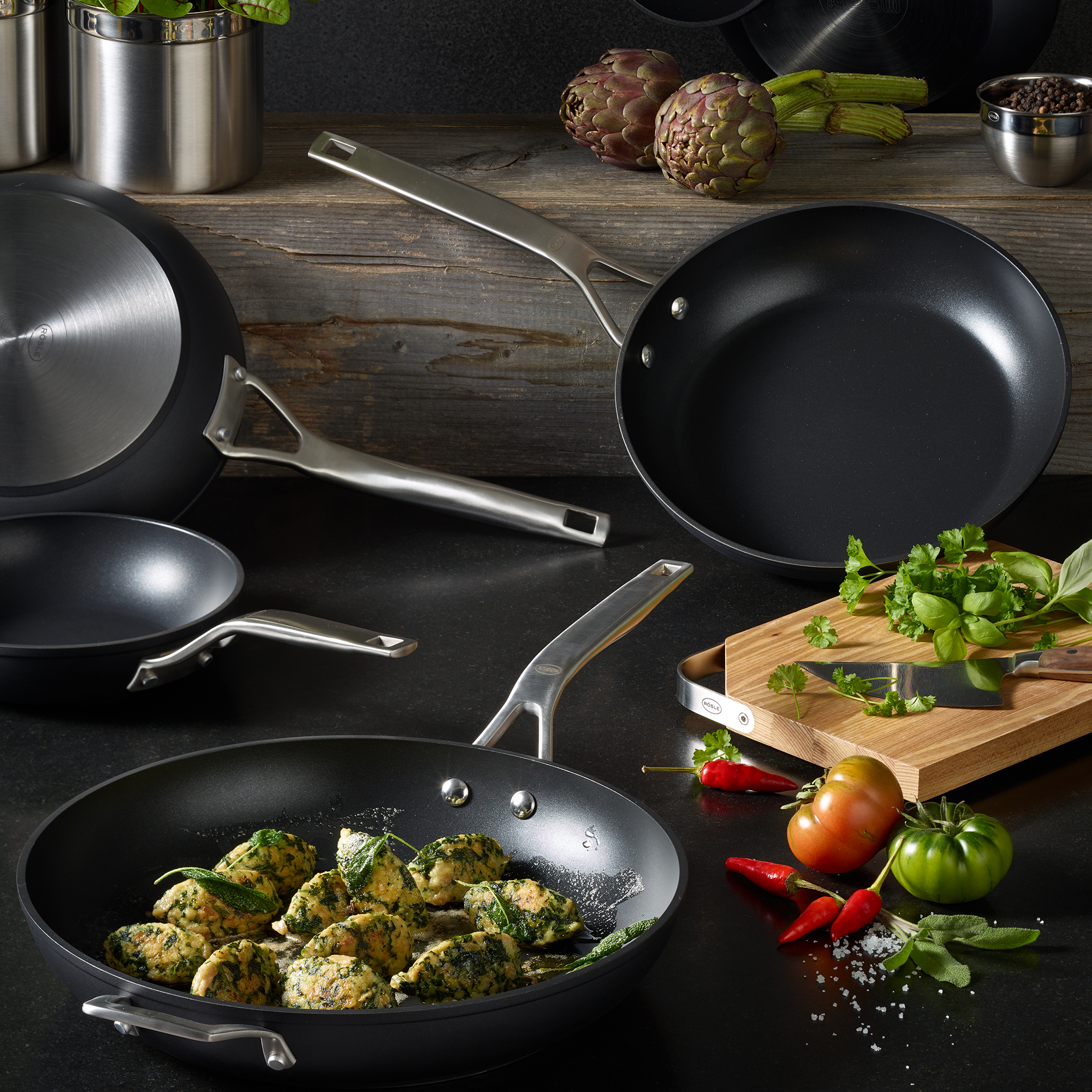 RÖSLE ProPlex Bratpfanne 32 cm mit Kräuterknödeln Bratpfanne ProPlex, 32 cm, schwarz, mit gefüllten Kräuterknödeln, umgeben von weiteren Pfannen...