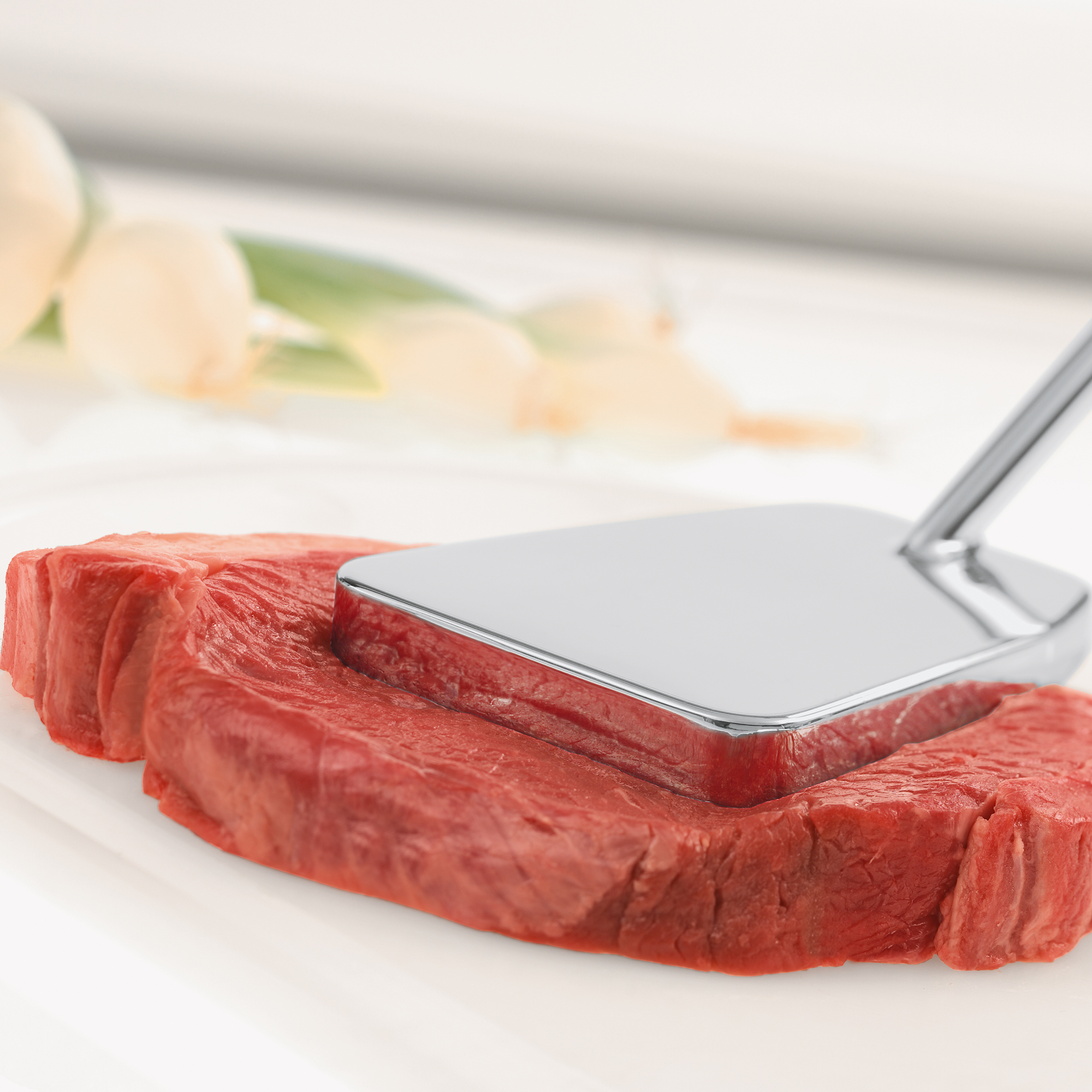 RÖSLE meat plater Stainless steel meat platter, rectangular shape, placed on raw piece of meat.
