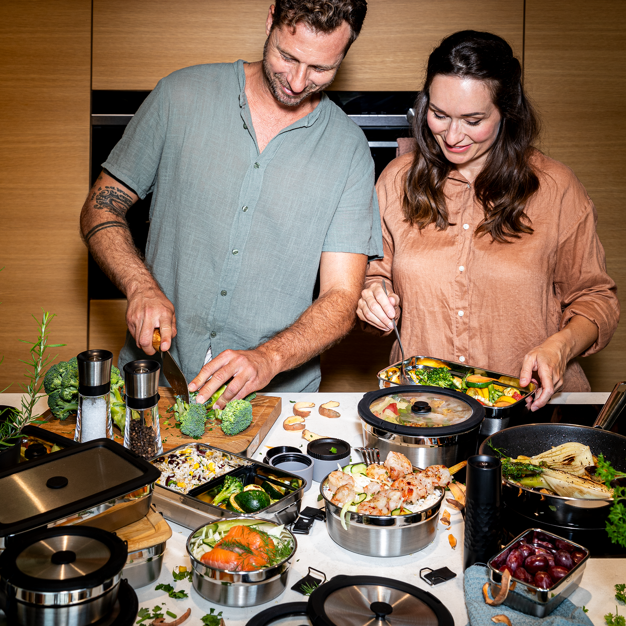 Flexx2go 1,4l Behälter in einer Küche, während ein Mann und eine Frau gemeinsam Gemüse zubereiten.