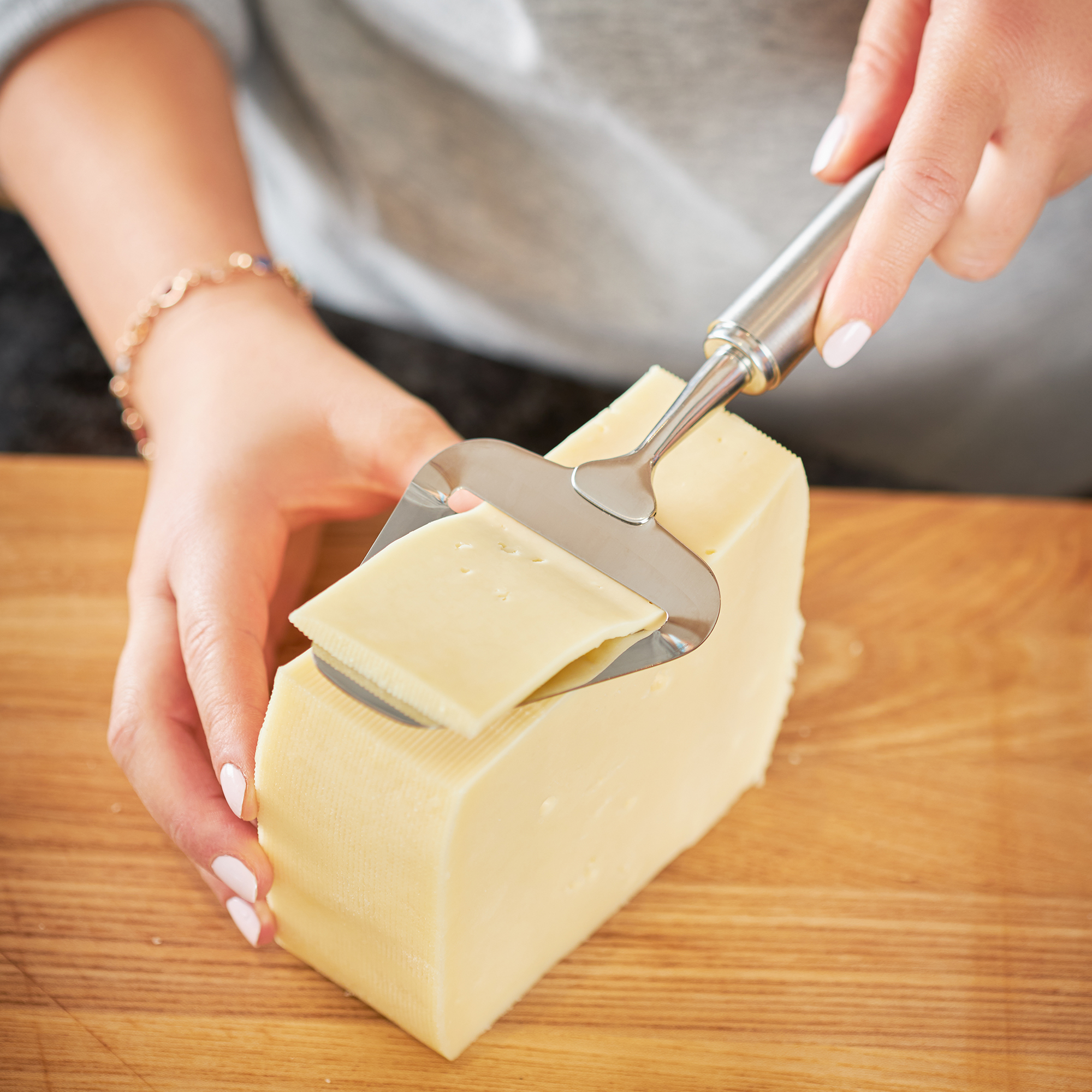 RÖSLE cheese slicer in action Stainless steel cheese slicer, 24 cm, is used to cut even slices of cheese from a block.