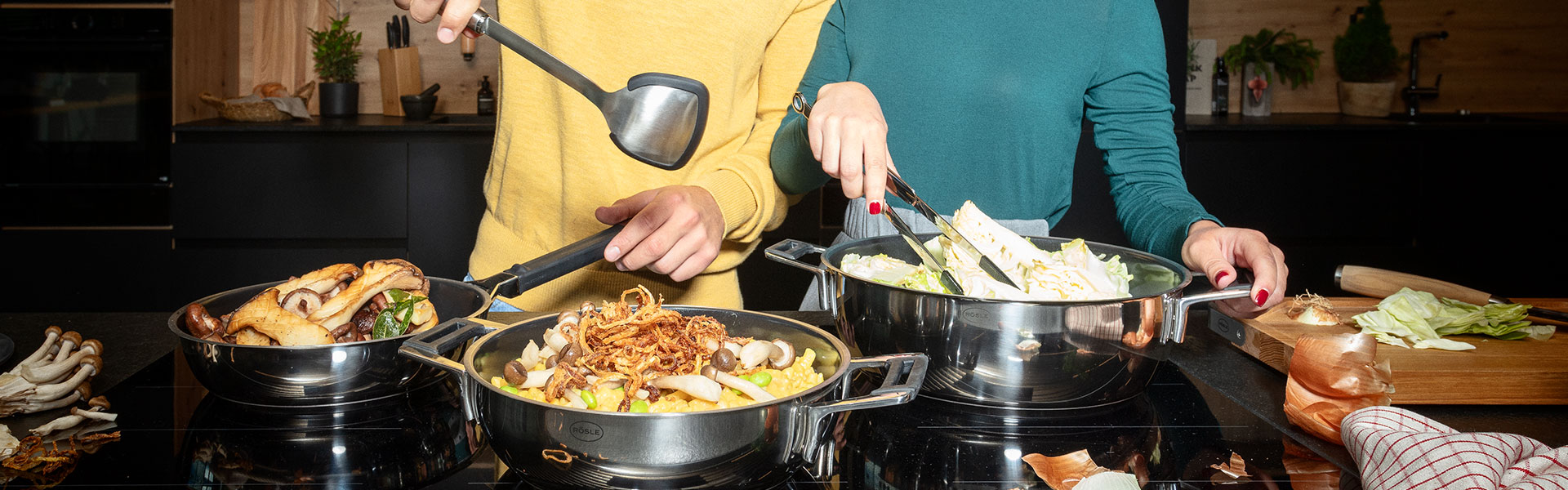 Kochszenario mit zwei Personen in der Küche Zwei Personen in der Küche, die mit Kochlöffeln in Töpfen mit Gemüse und Pilzen rühren.