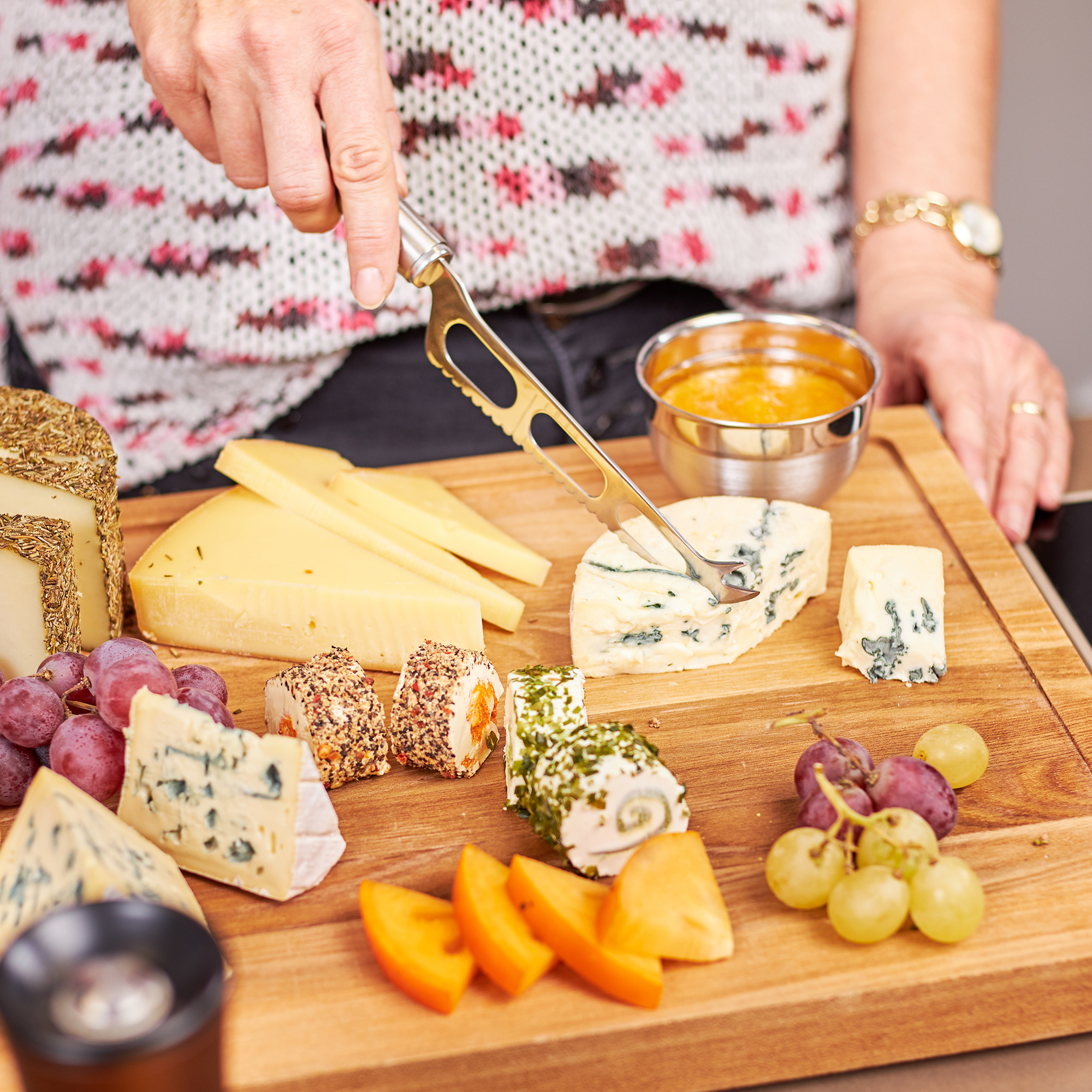 RÖSLE Käsemesser auf Käseplatte Käsemesser aus Edelstahl, verwendet zum Schneiden von verschiedenen Käsesorten auf einem Holzbrett.